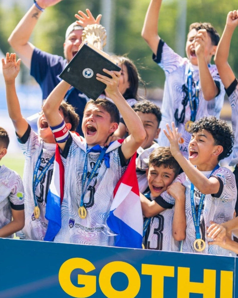 Children celebrating with raised hands and a flag, with 'Gothia' branding in the background.
