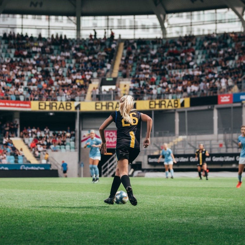 Soccer player in action on a field with spectators in the stands.